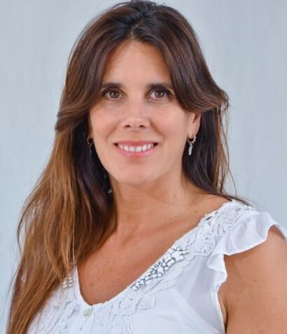 Laura Zommer durante una charla sobre desinformación en medios digitales, sosteniendo un micrófono frente a una pantalla con gráficos de datos.