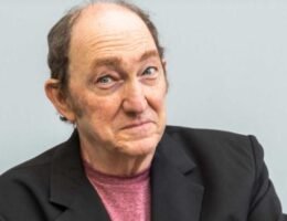 Adrián Stoppelman durante una emisión radial en estudio, con micrófono y auriculares, en plena editorial humorística.