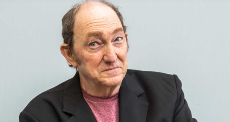 Adrián Stoppelman durante una emisión radial en estudio, con micrófono y auriculares, en plena editorial humorística.