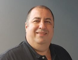 Martín Salvetti en un estudio de radio escolar, frente al micrófono, rodeado de alumnos.