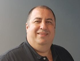 Martín Salvetti en un estudio de radio escolar, frente al micrófono, rodeado de alumnos.